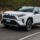 Toyota RAV4 blanche qui roule à toute vitesse sur une route bordée d'arbres