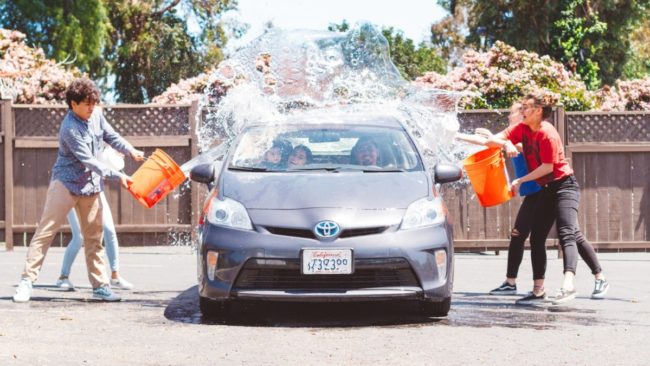 Enfants qui jettent des seaux d'eau sur une voiture toyota gégo pour la laver