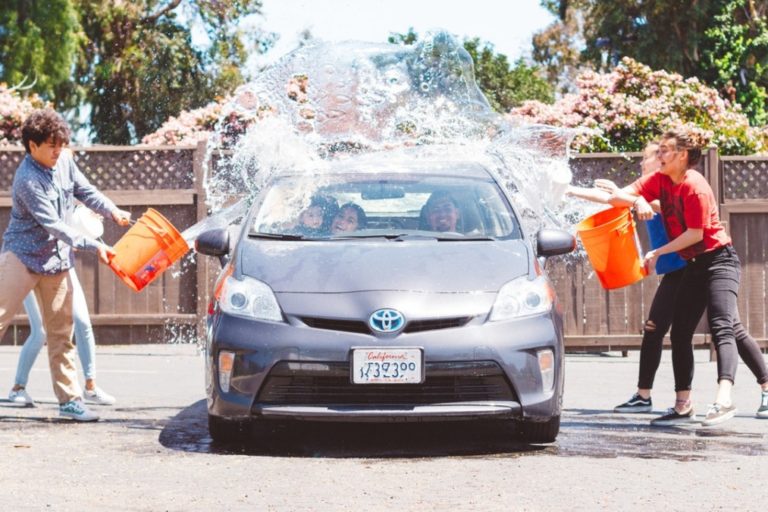 Enfants qui jettent des seaux d'eau sur une voiture toyota gégo pour la laver