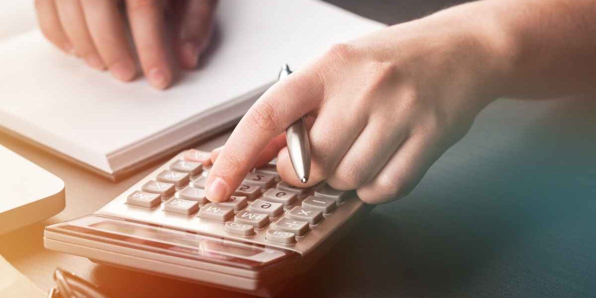 TOYOTA-fiscalite-voiture-societe Homme assis à un bureau avec un cahier ouvert et une calculette en train de calculer la fiscalité de sa voiture de société