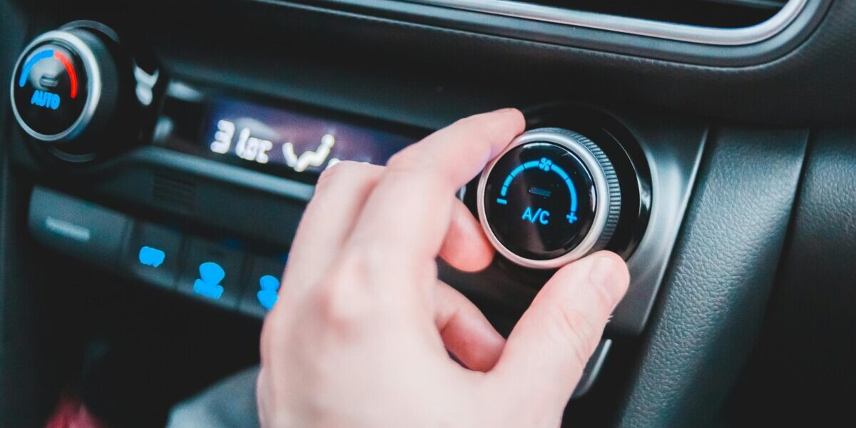 Main d'homme qui règle le bouton de climatisation de sa voiture