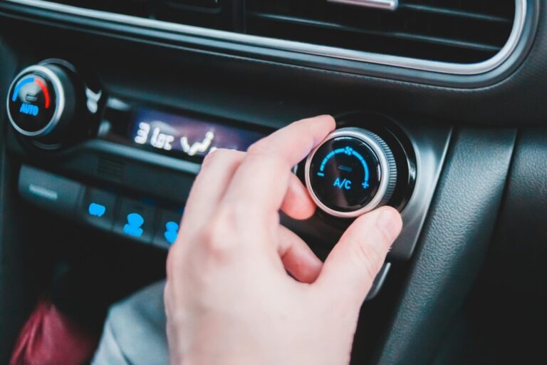 Main d'homme qui règle le bouton de climatisation de sa voiture