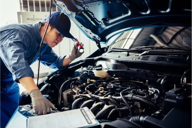 Contrôle technique d'une voiture par un mécanicien qui vérifier le moteur